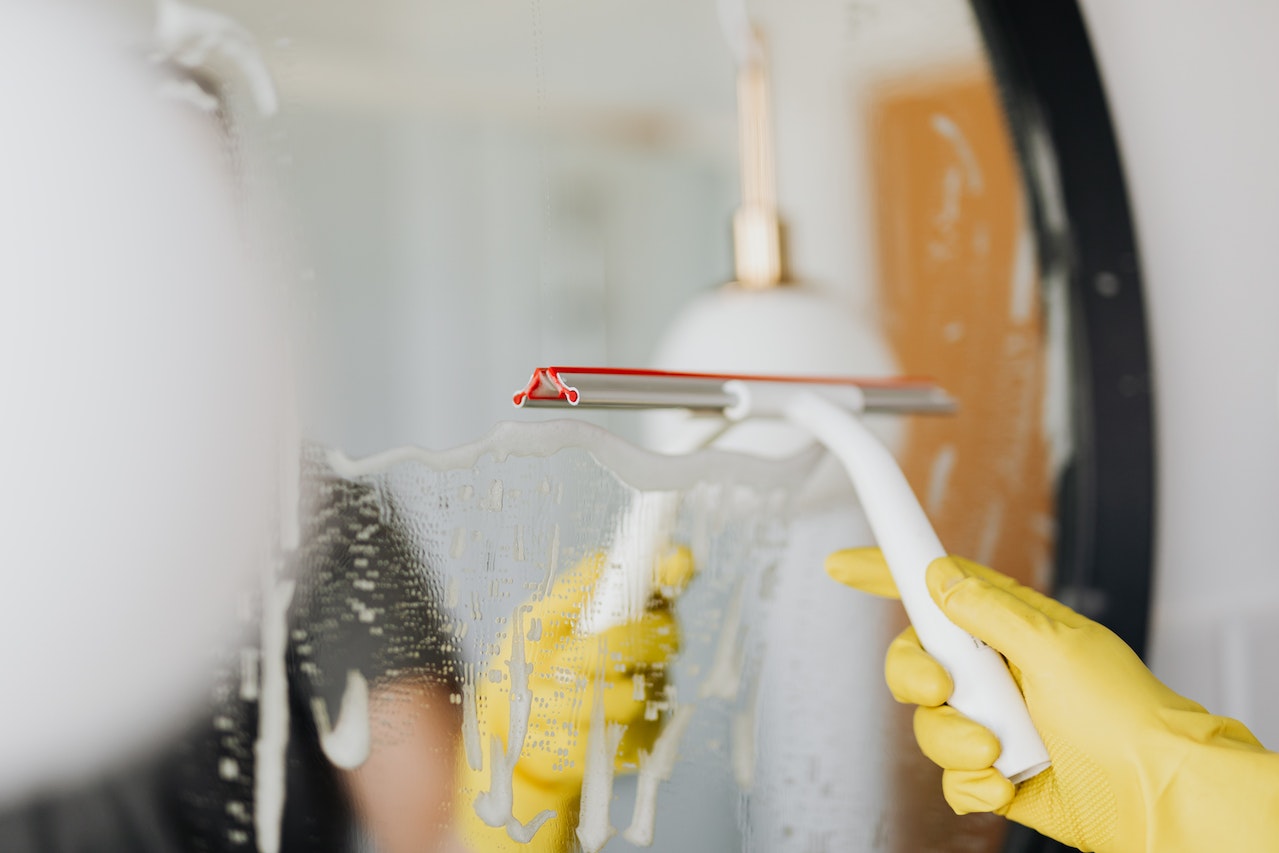 A person cleaning a mirror in a bathroom